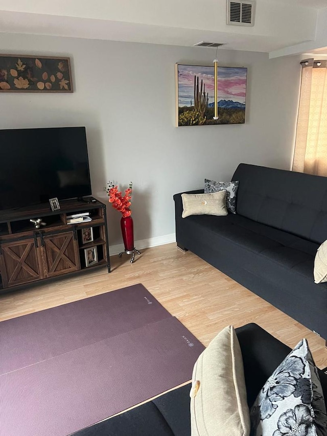 living room featuring wood finished floors, visible vents, and baseboards