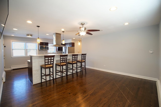 kitchen featuring a baseboard heating unit, a kitchen bar, appliances with stainless steel finishes, island exhaust hood, and dark wood-style floors