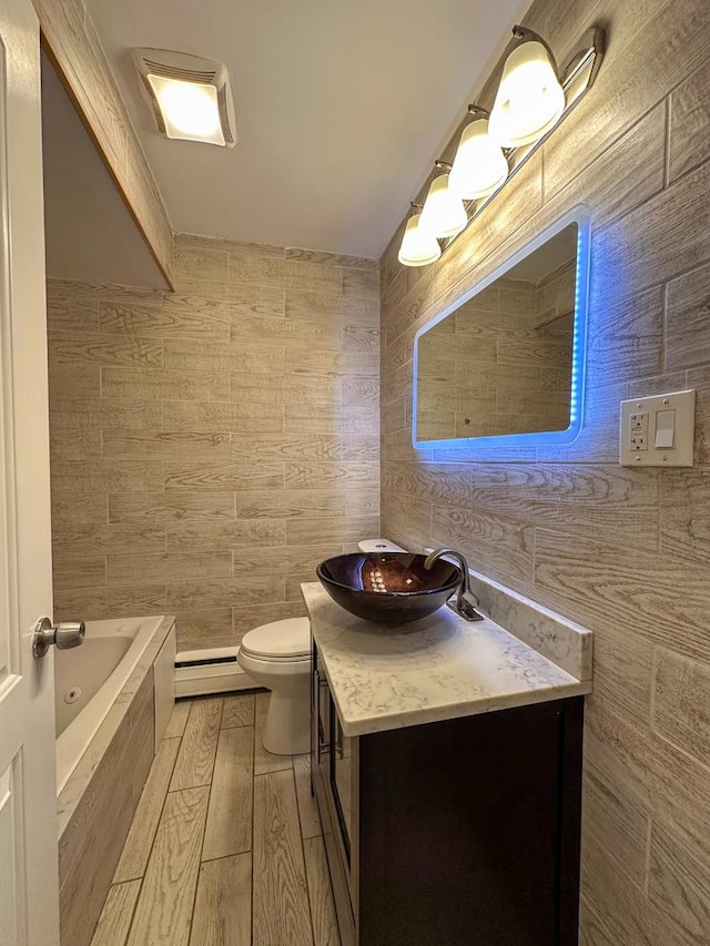 bathroom with vanity, wood finished floors, tiled bath, tile walls, and toilet