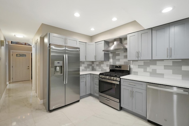 kitchen featuring marble finish floor, wall chimney exhaust hood, gray cabinets, and stainless steel appliances