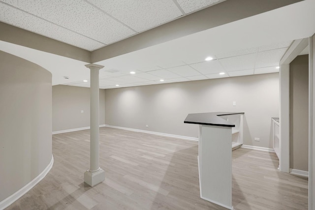 finished basement with light wood-style flooring, baseboards, a drop ceiling, and recessed lighting