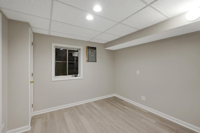 unfurnished room with a drop ceiling, recessed lighting, baseboards, electric panel, and light wood finished floors