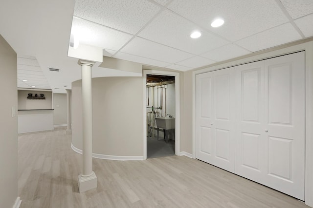 below grade area with light wood-type flooring, visible vents, a paneled ceiling, and baseboards