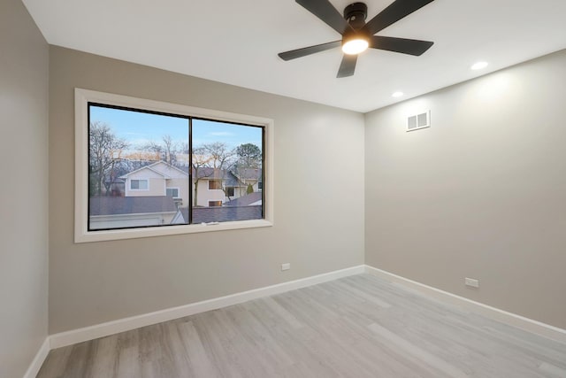 unfurnished room featuring a ceiling fan, visible vents, baseboards, and wood finished floors