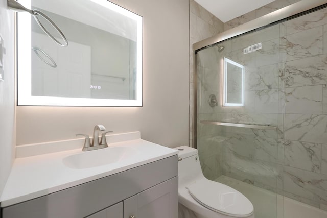 bathroom with a shower stall, vanity, and toilet