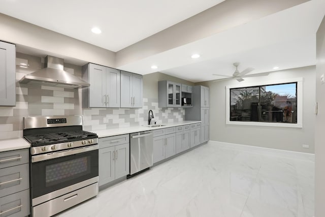 kitchen with stainless steel appliances, gray cabinetry, marble finish floor, and wall chimney exhaust hood