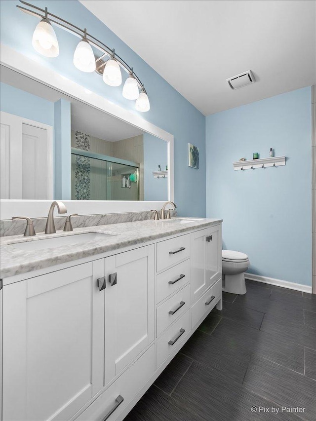 bathroom with a sink, a shower stall, toilet, and double vanity