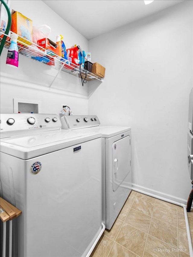 clothes washing area with laundry area, washer and clothes dryer, light tile patterned flooring, and baseboards