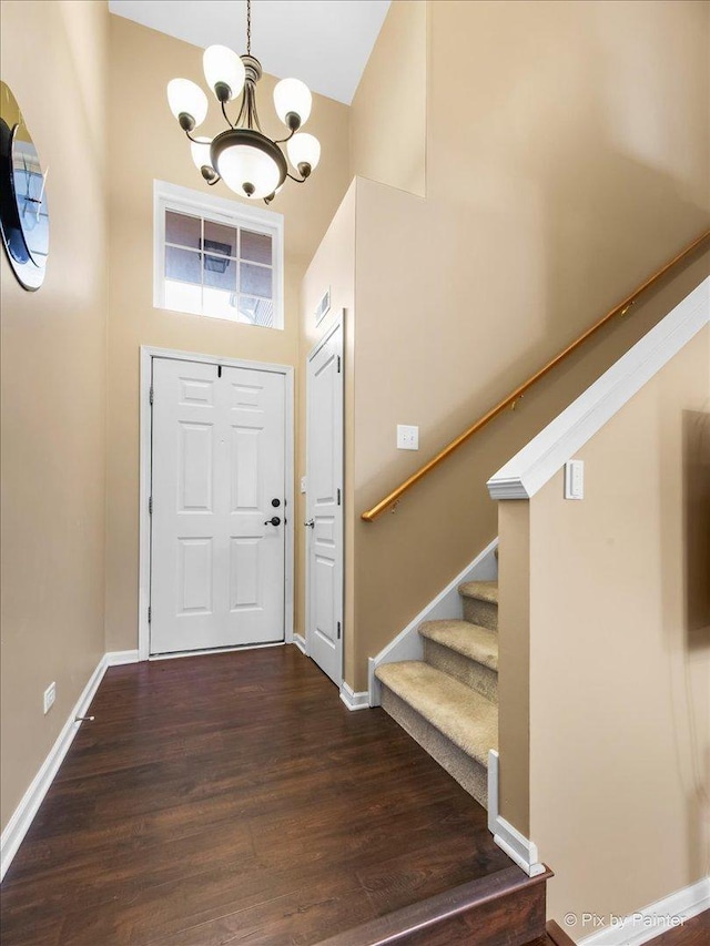 entryway with a chandelier, dark wood-style flooring, baseboards, and stairs