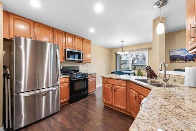 kitchen featuring dark wood-style floors, light stone counters, stainless steel appliances, pendant lighting, and a sink