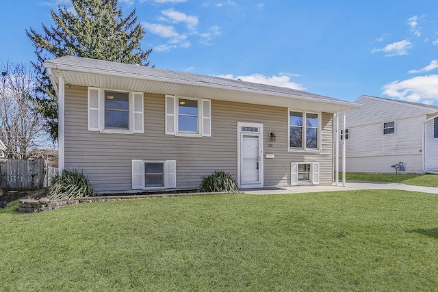 bi-level home featuring a front lawn, a patio area, and fence