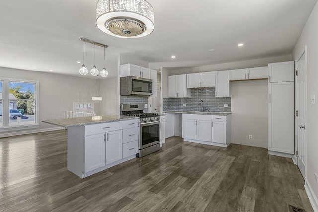 kitchen featuring tasteful backsplash, white cabinets, appliances with stainless steel finishes, and dark wood-type flooring