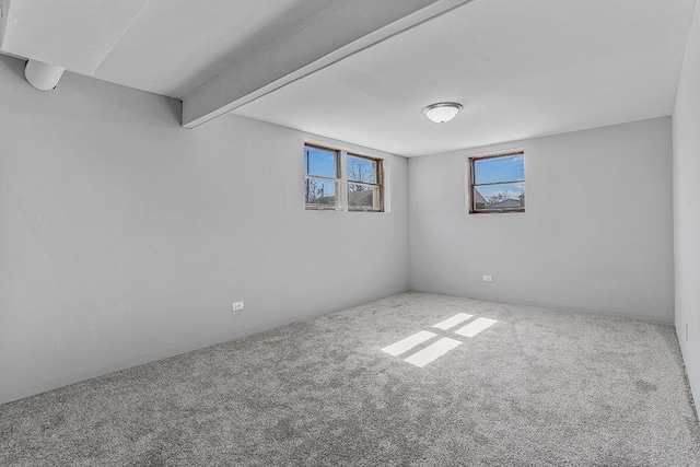 unfurnished room with beam ceiling and carpet flooring