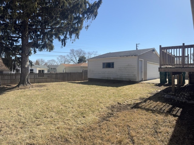 view of yard featuring a deck, an outbuilding, fence, and a detached garage