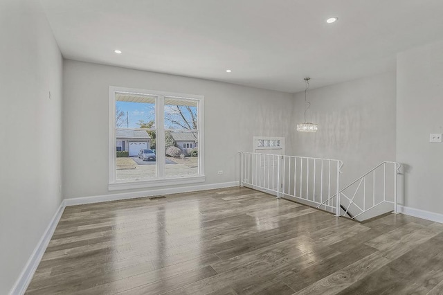 unfurnished room featuring visible vents, wood finished floors, recessed lighting, an inviting chandelier, and baseboards