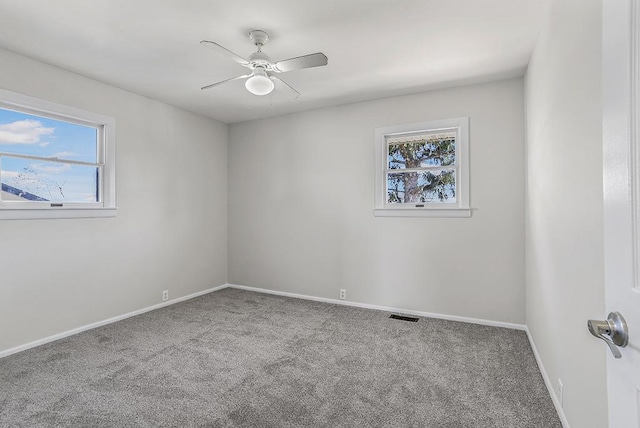 carpeted empty room featuring plenty of natural light, a ceiling fan, and baseboards