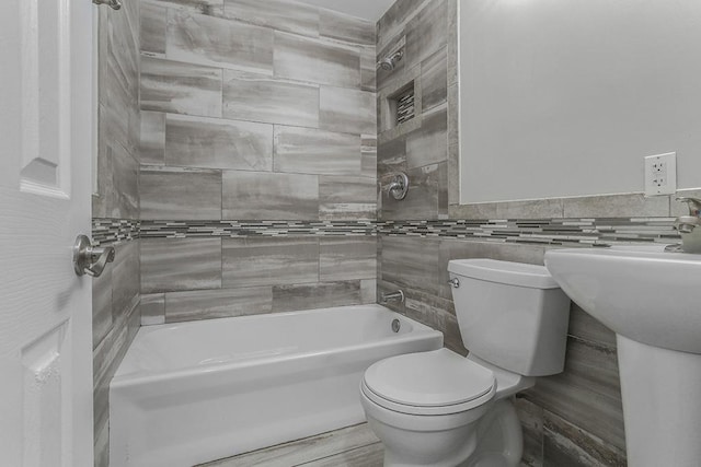 bathroom with tile walls, toilet, and shower / bathtub combination