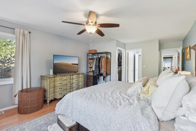 bedroom with visible vents, a ceiling fan, wood finished floors, a closet, and a spacious closet