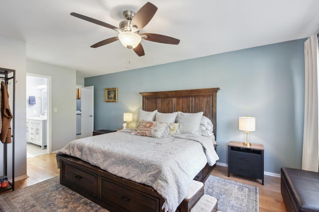 bedroom featuring baseboards, ensuite bathroom, wood finished floors, a ceiling fan, and a sink