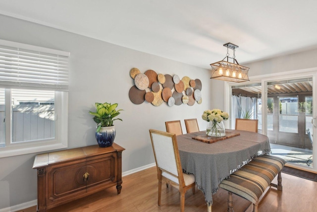 dining room featuring light wood finished floors, a notable chandelier, and baseboards