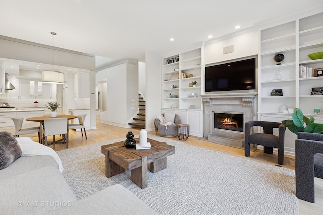 living room with a fireplace, recessed lighting, light wood finished floors, and stairs