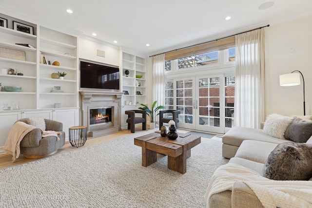 living area with french doors, wood finished floors, a glass covered fireplace, built in features, and recessed lighting