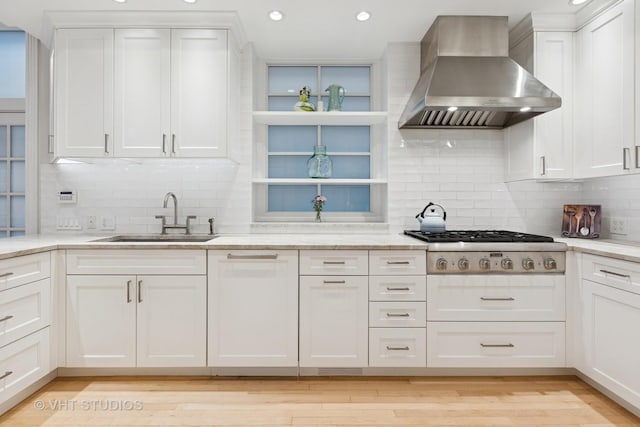 kitchen with white cabinetry, stainless steel gas stovetop, wall chimney exhaust hood, and a sink