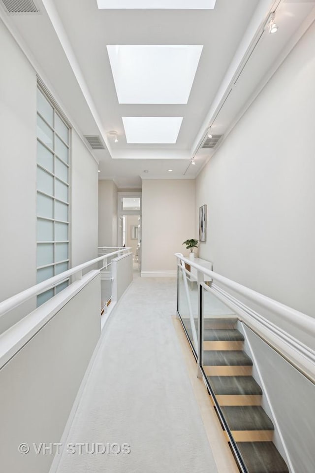 corridor featuring a skylight, baseboards, and visible vents
