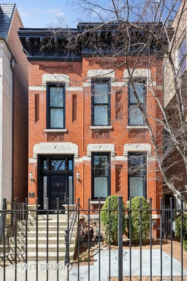 view of front of property with a fenced front yard and brick siding