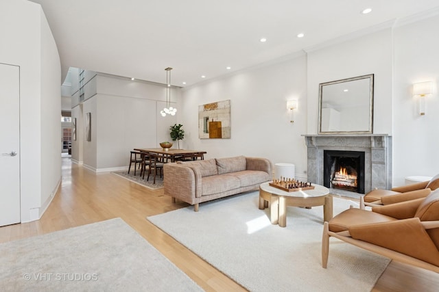 living area with baseboards, light wood-style floors, recessed lighting, and a premium fireplace