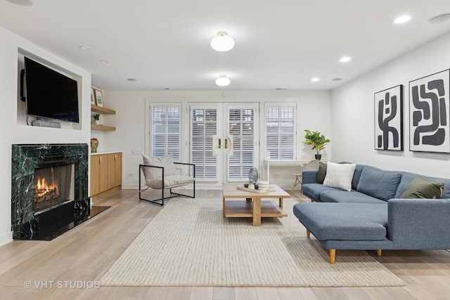 living area with baseboards, light wood-type flooring, recessed lighting, and a fireplace