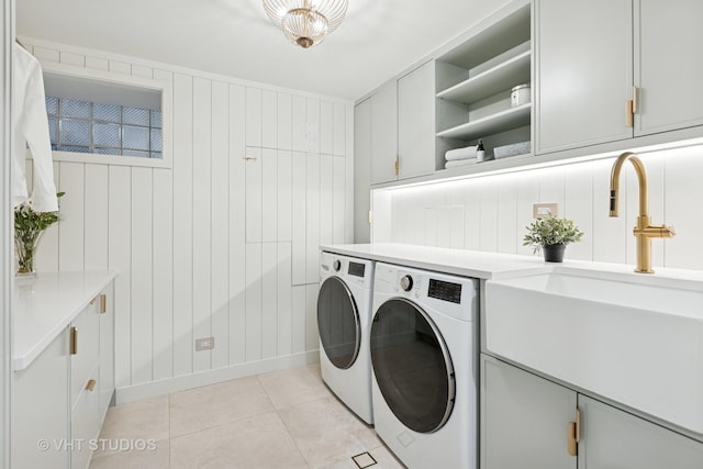 washroom featuring washer and clothes dryer, cabinet space, a sink, and light tile patterned floors