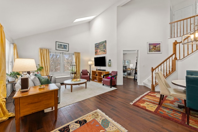 living area featuring high vaulted ceiling, a skylight, stairway, and hardwood / wood-style floors