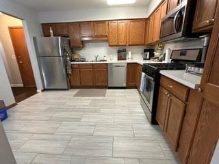 kitchen with brown cabinets, appliances with stainless steel finishes, light countertops, and a sink