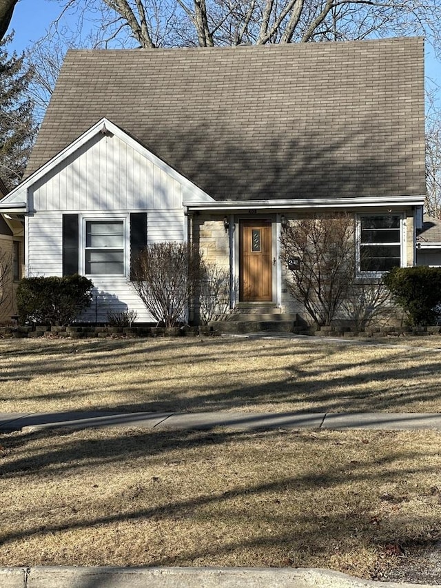 view of front of house with a shingled roof and a front lawn