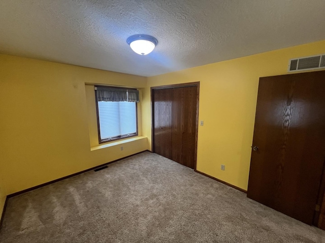 unfurnished bedroom with carpet floors, a textured ceiling, visible vents, and a closet