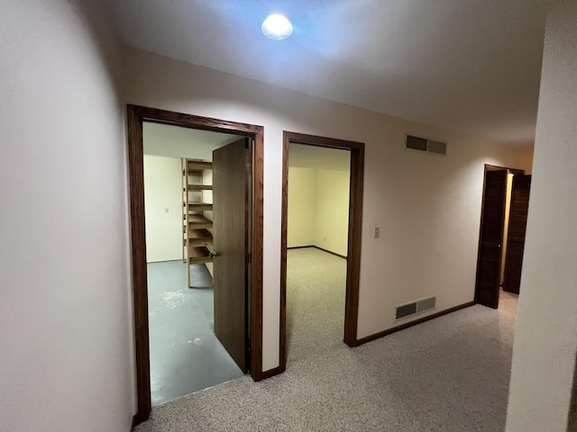 corridor featuring light carpet, visible vents, and baseboards