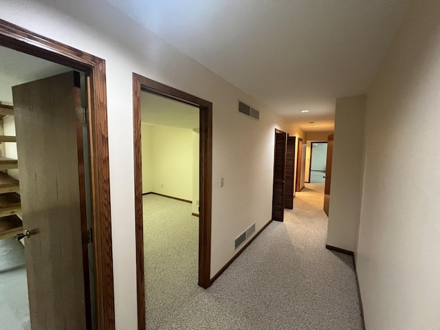 corridor with carpet, visible vents, and baseboards