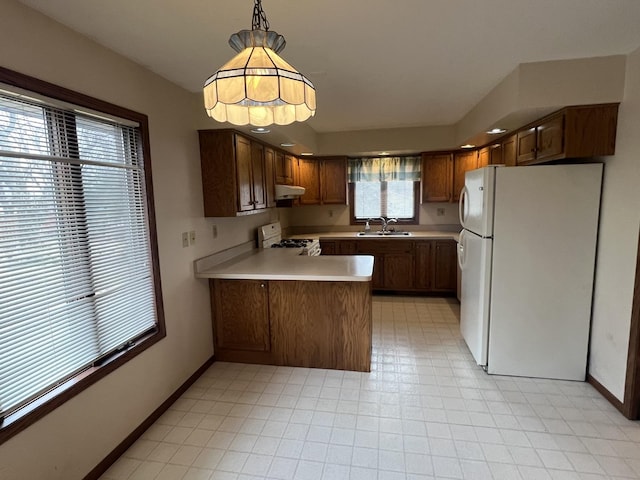 kitchen with white appliances, a peninsula, light countertops, under cabinet range hood, and a sink