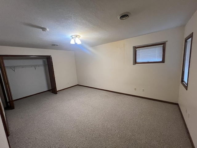 unfurnished bedroom with visible vents, light carpet, a textured ceiling, and baseboards