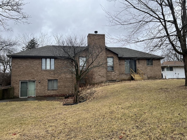 rear view of property with brick siding, a chimney, a shingled roof, a lawn, and entry steps