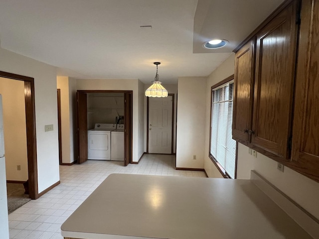 kitchen featuring pendant lighting, independent washer and dryer, dark brown cabinetry, and baseboards