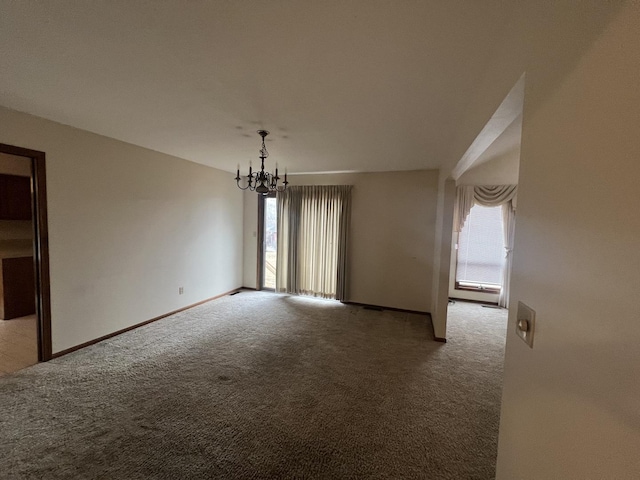 unfurnished room with a wealth of natural light, a notable chandelier, baseboards, and carpet flooring