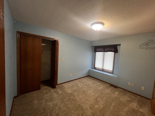 unfurnished bedroom with carpet floors, a closet, visible vents, a textured ceiling, and baseboards