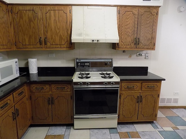 kitchen with extractor fan, white appliances, visible vents, tasteful backsplash, and dark countertops