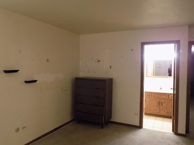 unfurnished bedroom featuring light carpet, ensuite bath, and baseboards