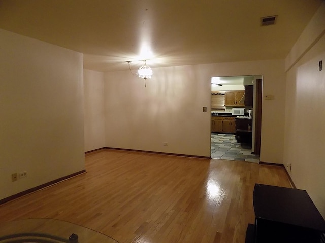 empty room featuring light wood-style flooring, visible vents, and baseboards