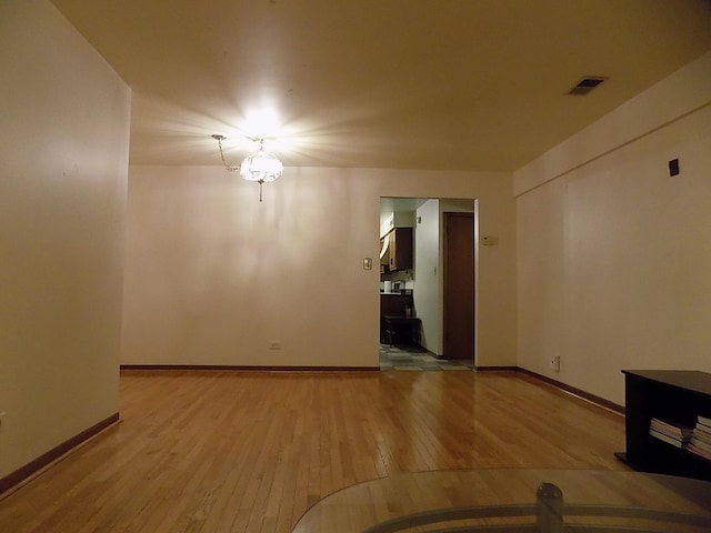 unfurnished room with hardwood / wood-style floors, visible vents, and baseboards