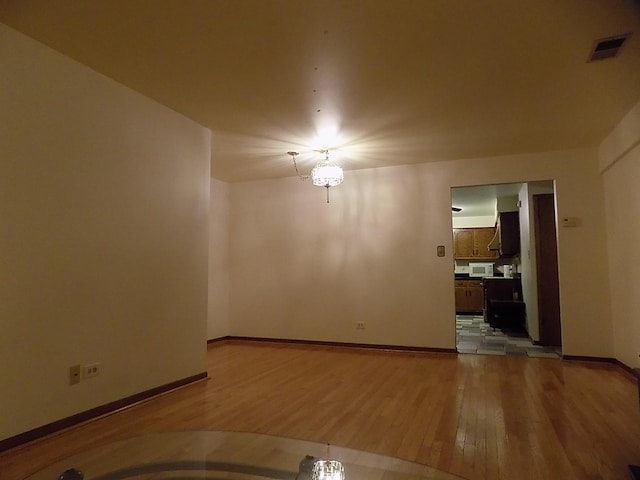 unfurnished room featuring light wood-style floors, visible vents, and baseboards