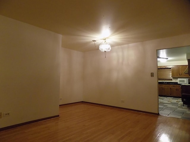 spare room featuring baseboards and wood finished floors